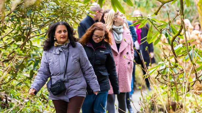 A group of visits are seen on a path walking through Bodnant Garden in Wales